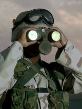A soldier with binoculars guards a Patriot Missile launcher.